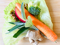 Auf einem Salatblatt angerichtet: Eine Möhre, ein Stück Apfel, Walnüsse, Brokkoli, Ingwer und Salbei